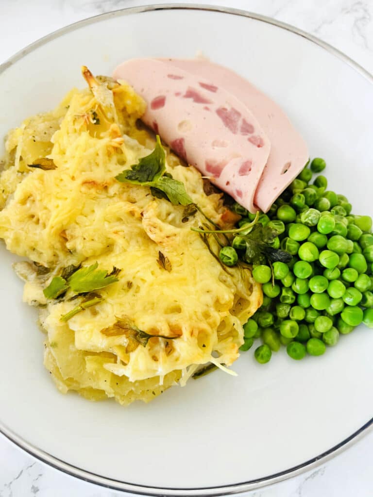 Cheesy potatoes gratin with green peas and smoked ham
