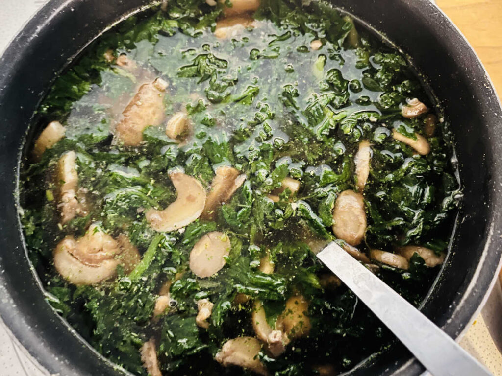 spinach and mushrooms cooking in a pot