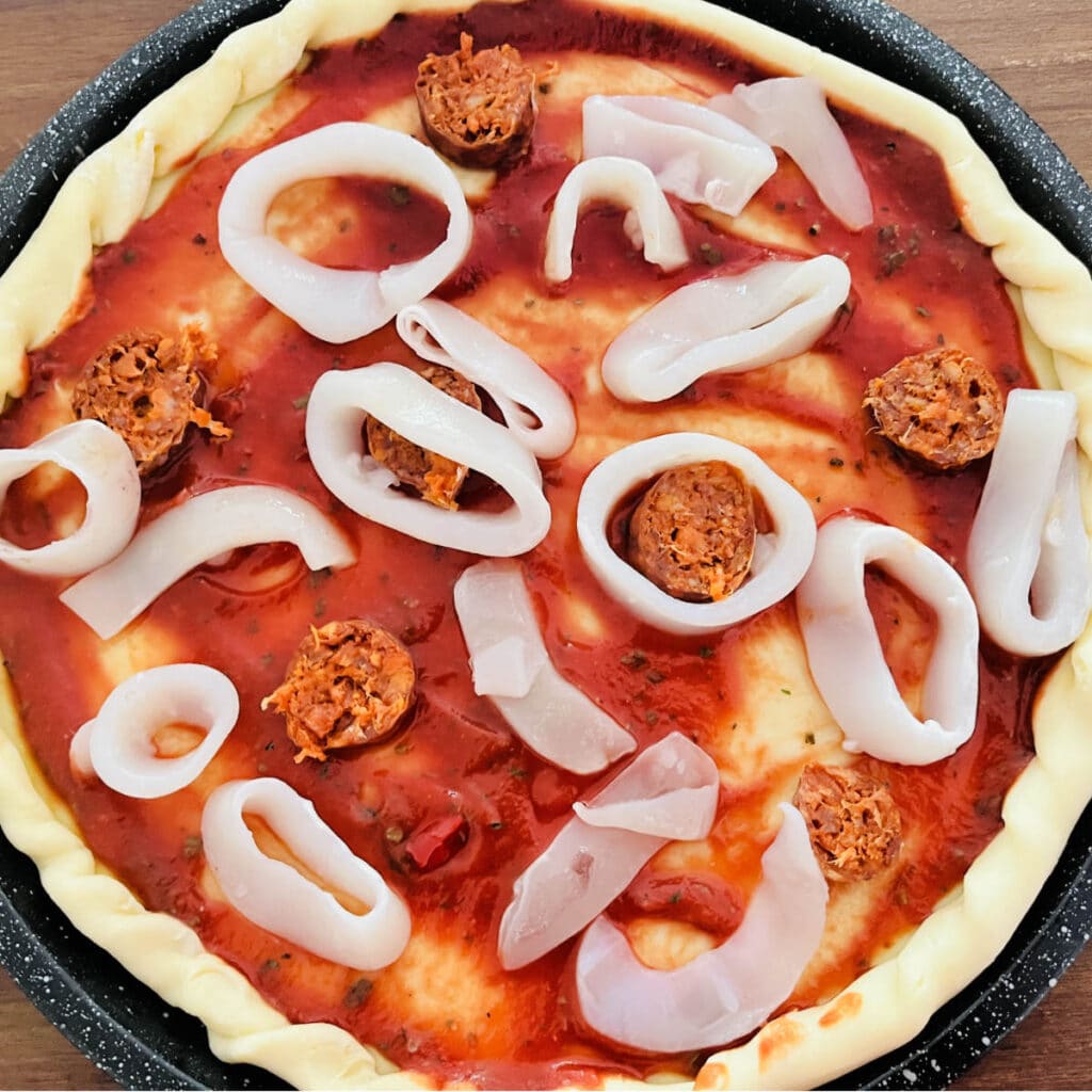 Calamari rings and chorizo on a pizza base with tomato sauce