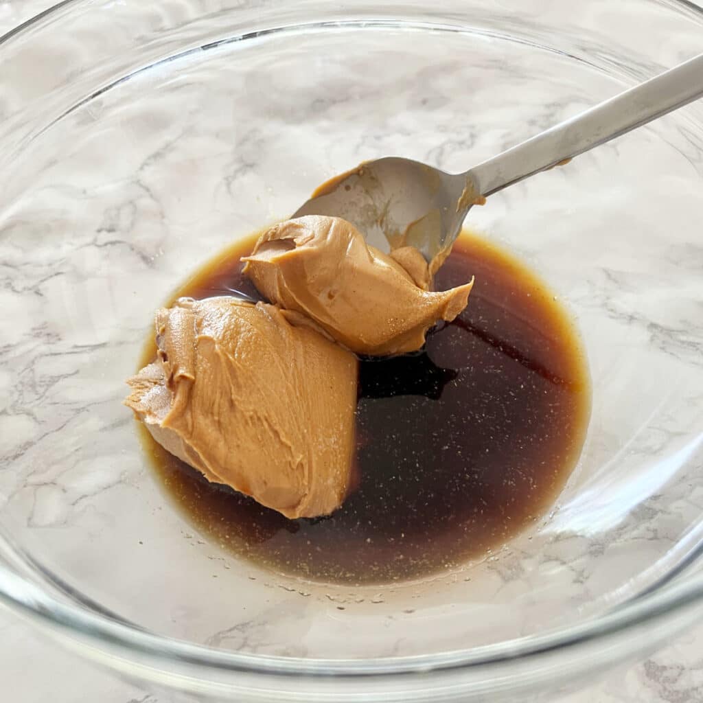 Soy sauce and peanut butter in a bowl before it is mixed