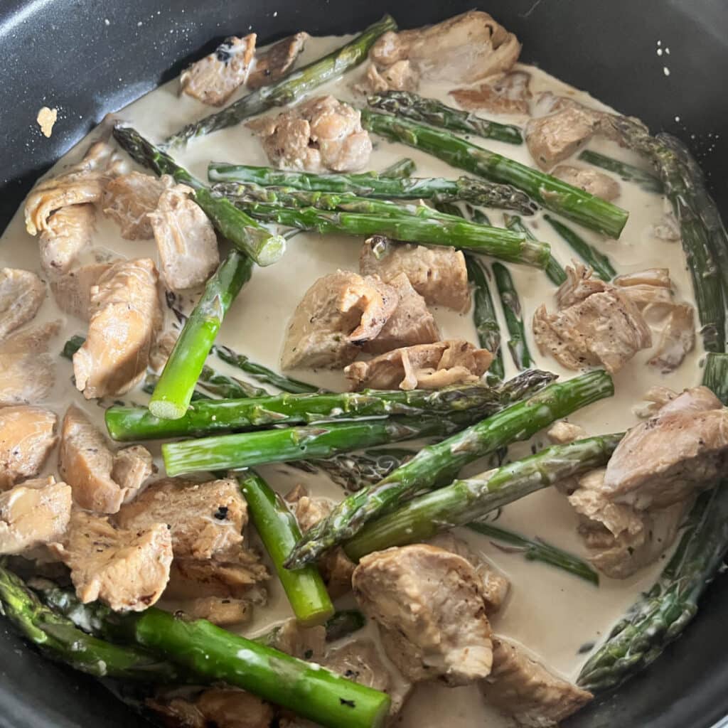 Adding cream to chicken and asparagus