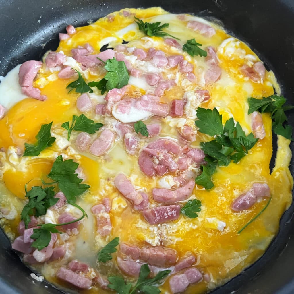 Eggs and bacon cooking with herbs